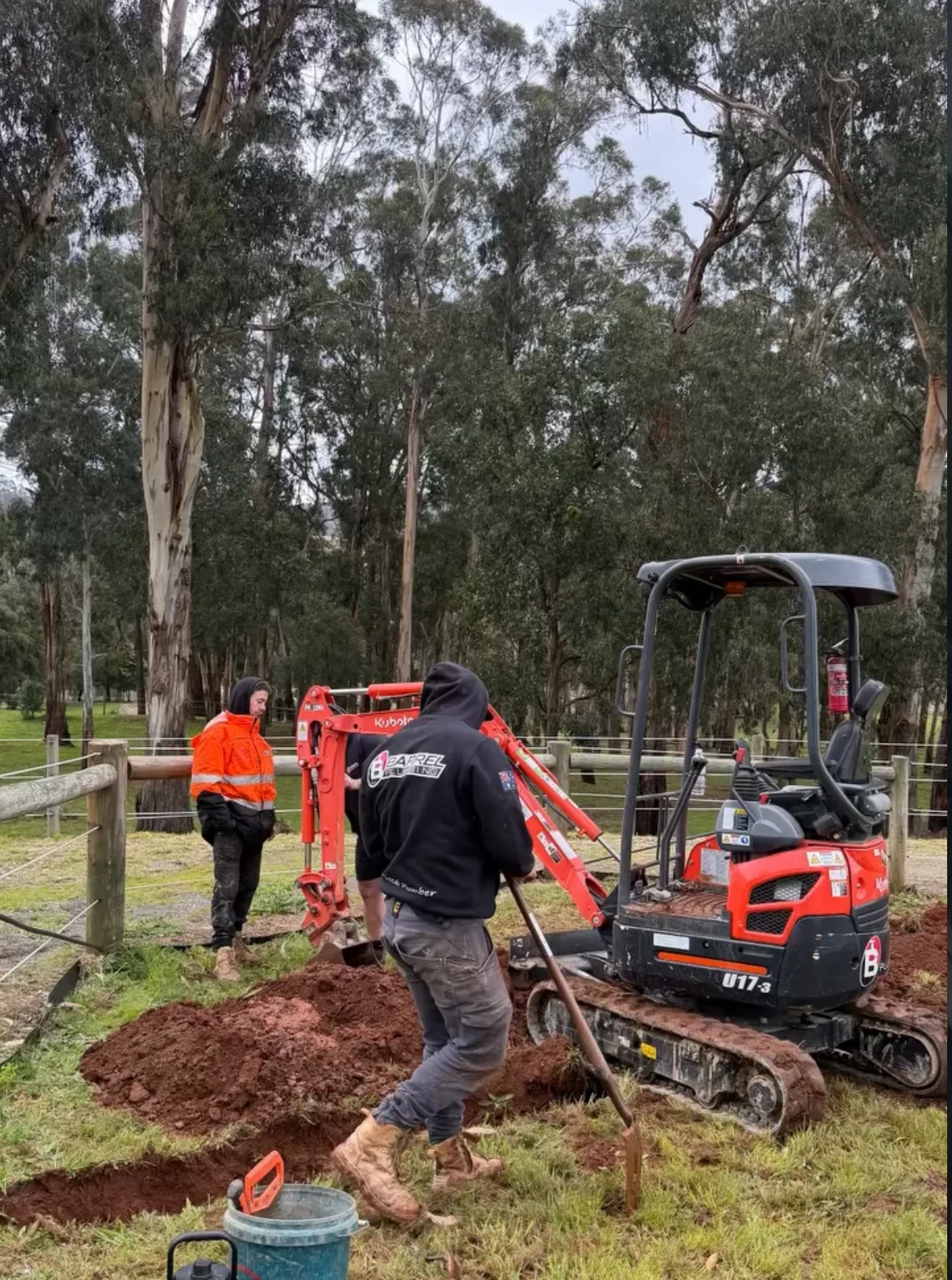 Barrel plumbers and their excavator installing underground pipework on a rural property